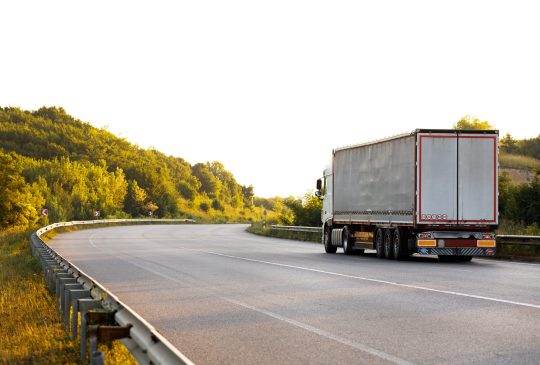 Arriving truck on the road in a rural landscape at sunset